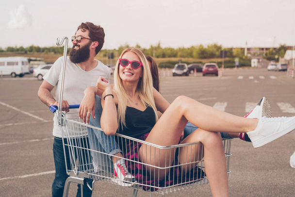 Man pushing shopping trolley with female friends - Foto, afbeelding