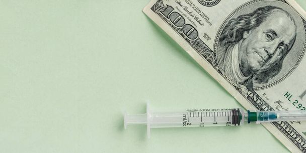 Money and syringe on green background, vaccination concept, high cost of medical servicesy, flat lay - Valokuva, kuva