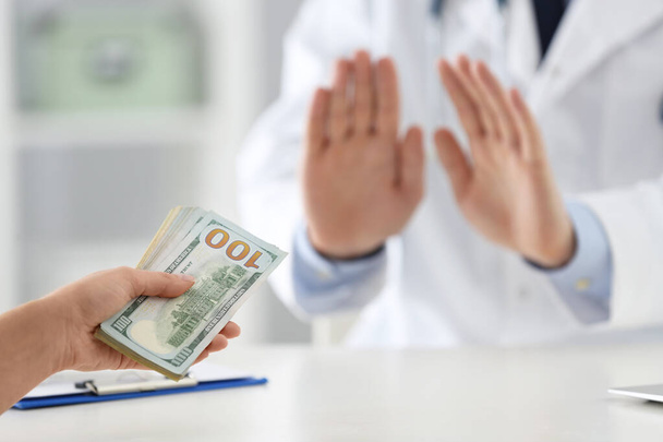 Doctor rejecting bribe in clinic, closeup. Corrupted medicine - Zdjęcie, obraz