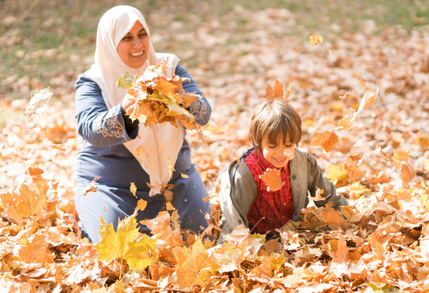 Muslim mother with little son in autumn leaves - Zdjęcie, obraz