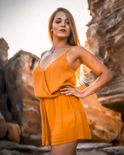 sunset portrait of beautiful young woman against rock - Foto, afbeelding