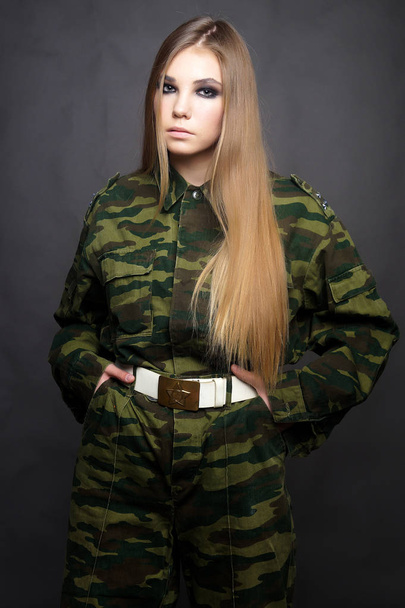 A girl soldier in camouflage clothing poses in a Studio - Zdjęcie, obraz