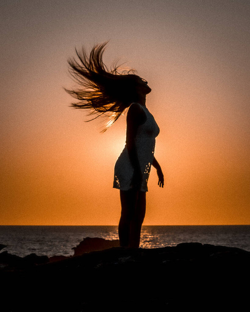sunset portrait of beautiful young woman at sea shore - 写真・画像