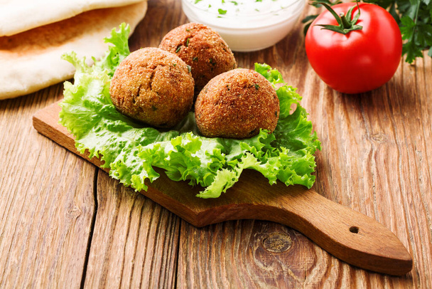 Chickpea falafel balls on a wooden desk with vegetables - Foto, immagini