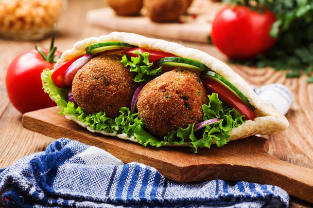 Falafel and fresh vegetables in pita bread on wooden table - Foto, imagen