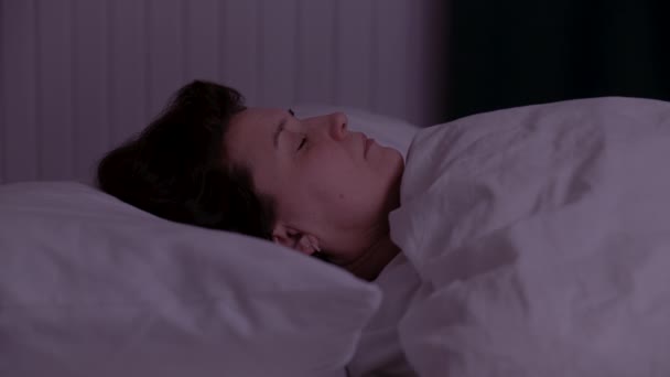 Adult woman sleeping on a bed at night. - Záběry, video