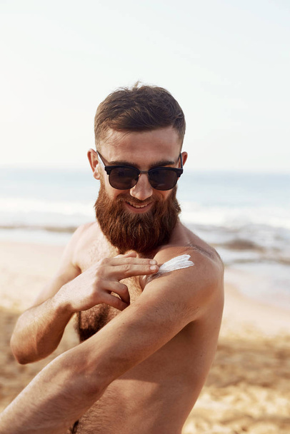 Handsome Man with beard, In Sunglasses Sunbathing With Sunscreen Lotion Body In Summer. Male Fitness Model Tanning Using Solar Block Cream For Healthy Tan. Skincare. Sun Skin Protection  - Fotoğraf, Görsel