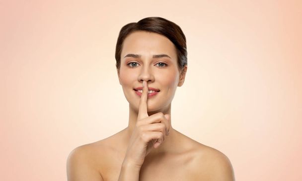 beautiful young woman holding finger on lips - Фото, изображение