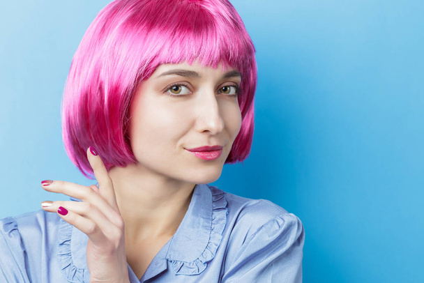 Woman wearing funny pink wig and smiling to camera - Photo, Image