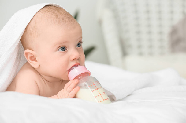 Retrato de bebé lindo bebiendo leche de biberón en la cama
 - Foto, Imagen