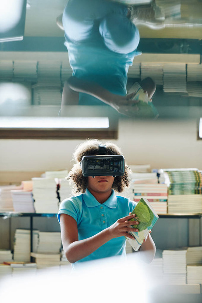 Portret van een jong meisje dat Vr-headset gebruikt om te studeren in een moderne schoolbibliotheek in een moderne schoolbibliotheek - Foto, afbeelding