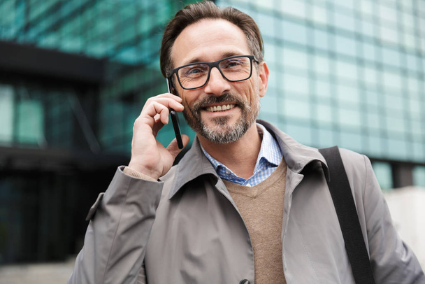 Image of smiling businessman talking on cellphone while standing - Foto, Imagen