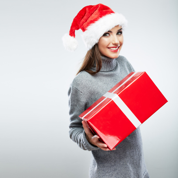 Portrait of woman in santa hat holding gift box - 写真・画像
