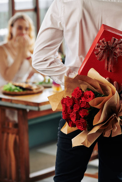 Unrecognizable guy bringing flowers and chocolate to his for his girlfriend on date in cafe - Foto, Imagem