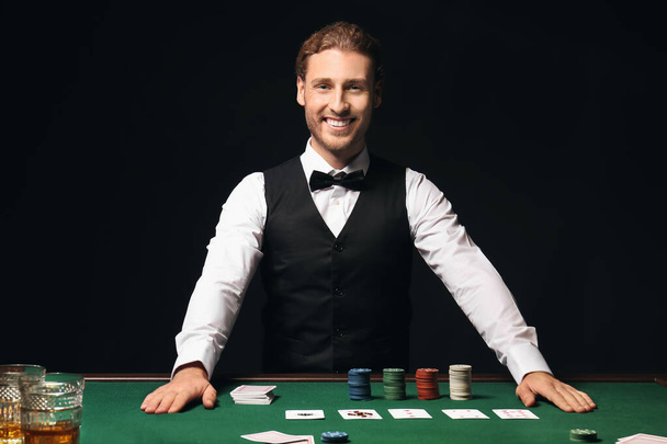 Jonge mannelijke bankier aan tafel in casino - Foto, afbeelding