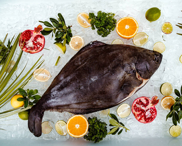 top view of raw fish placed on ice surrounded with fruit slices ____ - Φωτογραφία, εικόνα