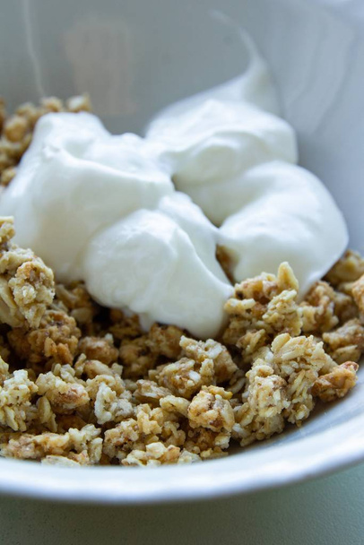 A closeup shot of muesli breakfast with Greek yogurt in a white bowl - Fotografie, Obrázek
