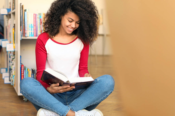Estudiante afroamericano leyendo libro mientras se prepara para el examen en la biblioteca
 - Foto, Imagen