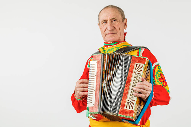 Un homme en costume national joue de l'accordéon. Isolé sur un w
 - Photo, image