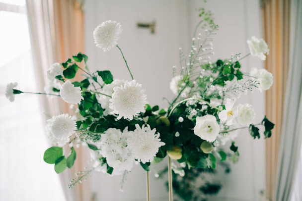 floral διακόσμηση τραπεζιών γάμου, ντελικάτα λευκά λουλούδια και κλαδιά φρέσκου πράσινου σε λευκή αίθουσα - Φωτογραφία, εικόνα