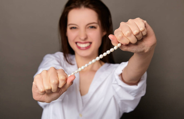Charming Caucasian girl with pearls in her hands. - Foto, Imagen