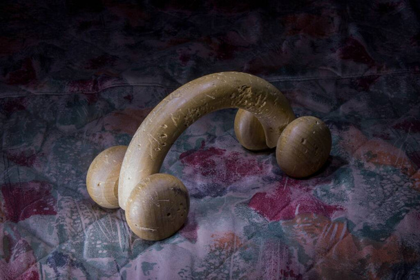 A closeup shot of an old wooden worn out back roller massager on a floral quilt - Photo, Image
