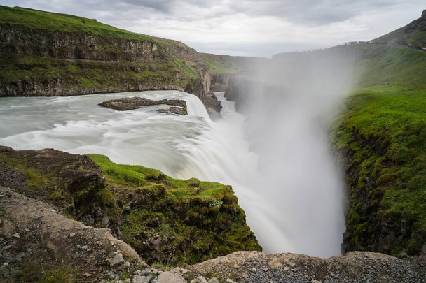 A beautiful shot of a waterfall in the middle of cliffs - Photo, image