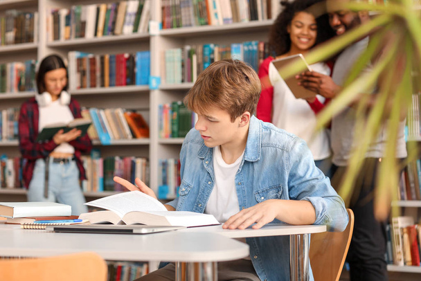 Estudante do sexo masculino ler livro enquanto se prepara para o exame na biblioteca
 - Foto, Imagem