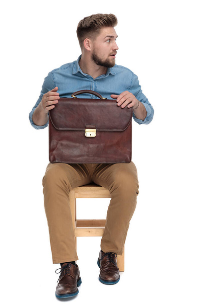 surprised young man looking to side and holding suitcase - Foto, immagini