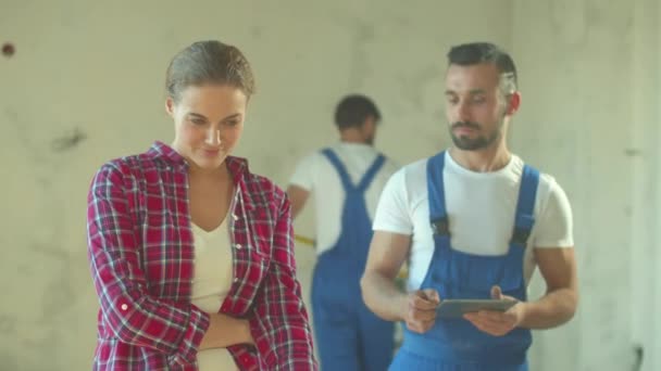 Happy woman talks about flat with builder - Záběry, video