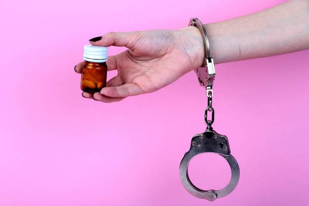 píldoras y tabletas esposadas manos sobre fondo rosa
 - Foto, imagen