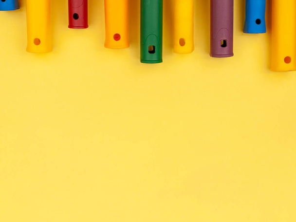 Colored handles for paint roller on a yellow background. - 写真・画像