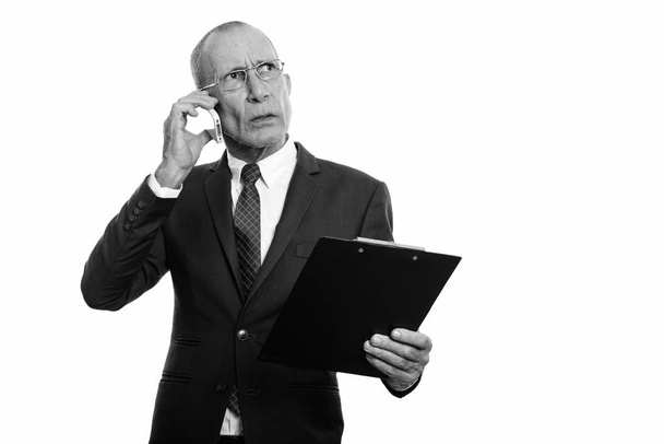 Studioaufnahme eines leitenden Geschäftsmannes im Anzug isoliert vor weißem Hintergrund in Schwarz-Weiß - Foto, Bild