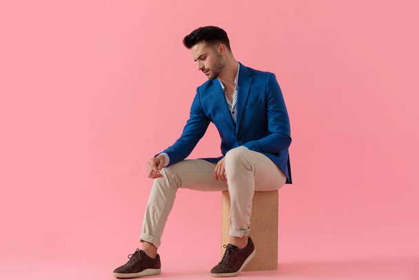 young smart casual man holding elbow on knee - Fotó, kép