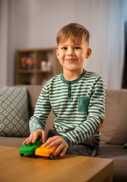 щасливий маленький хлопчик грає з іграшковими машинами вдома
 - Фото, зображення