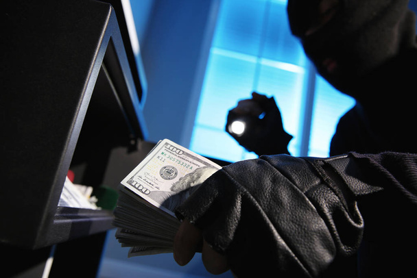 Thief taking money out of steel safe indoors at night, closeup - Valokuva, kuva