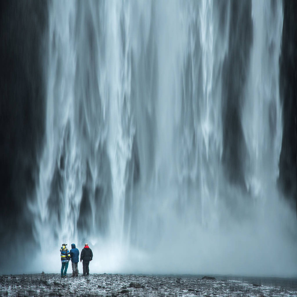 Tourist under the waterfall in Iceland, Adventure photo, edit space - Фото, изображение