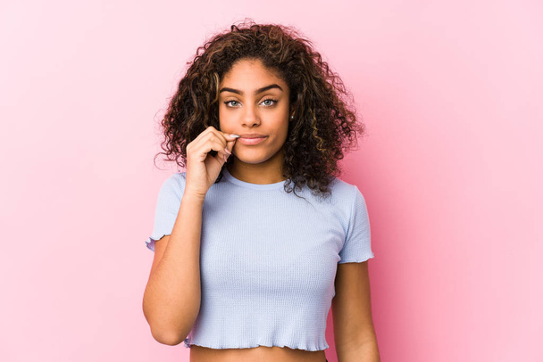 Young african american woman against a pink background with fingers on lips keeping a secret. - Photo, Image