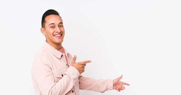 Jovem latino posando isolado animado apontando com os dedos indicador de distância
. - Foto, Imagem