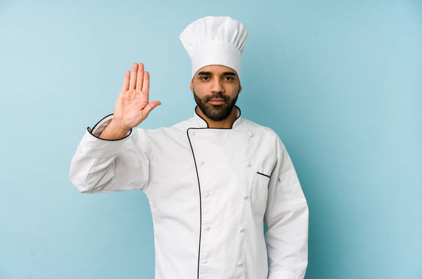 Young latin chef man isolated standing with outstretched hand showing stop sign, preventing you. - Fotó, kép