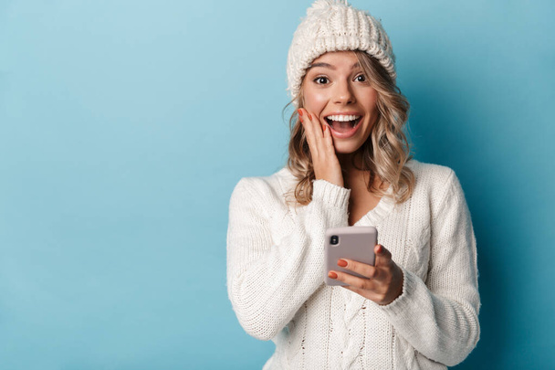 Portrait of cute excited woman smiling and using cellphone - Fotó, kép