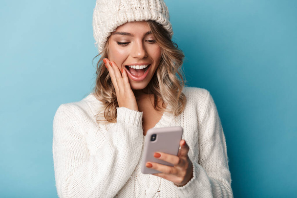 Portrait of cute surprised woman smiling and using cellphone - Foto, afbeelding