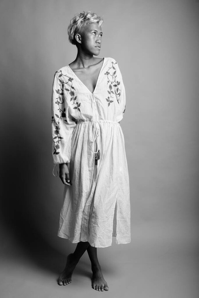 Studio shot de joven hermosa mujer asiática rebelde con pelo corto sobre fondo gris en blanco y negro
 - Foto, imagen