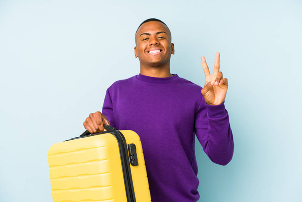 Junger Reisender mit Koffer zeigt Nummer zwei mit Fingern. - Foto, Bild