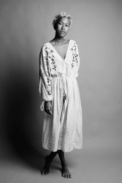 Studio shot de joven hermosa mujer asiática rebelde con pelo corto sobre fondo gris en blanco y negro
 - Foto, imagen