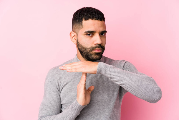 Young latin man against a pink background isolated showing a timeout gesture. - Photo, Image