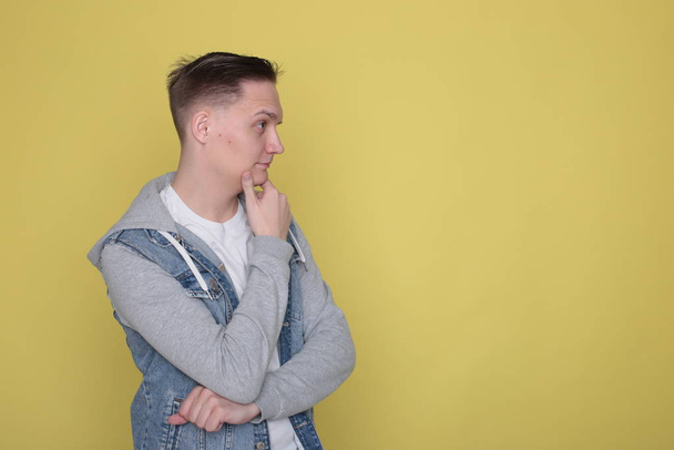 Stylish cool emotional guy in denim casual clothes on bright yellow background - Foto, afbeelding