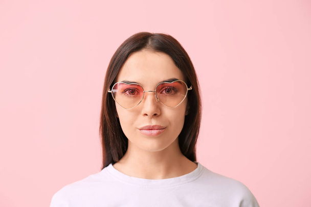 Mujer joven con gafas de sol elegantes sobre fondo de color
 - Foto, Imagen