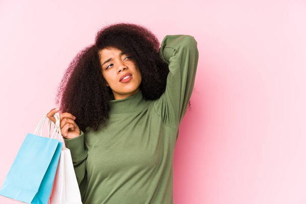 Young Afro woman with shopping bags isolated on pink background   - Fotó, kép