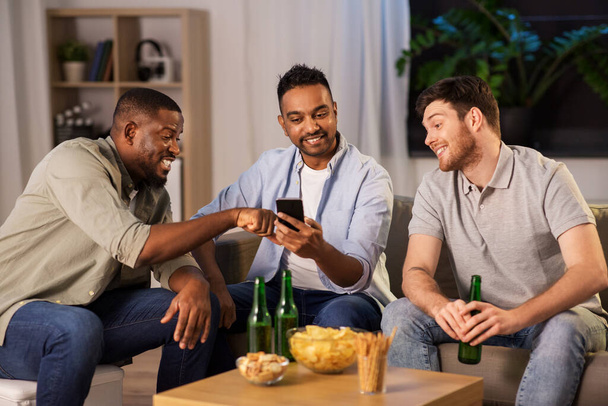 male friends with smartphone drinking beer at home - Foto, Imagen